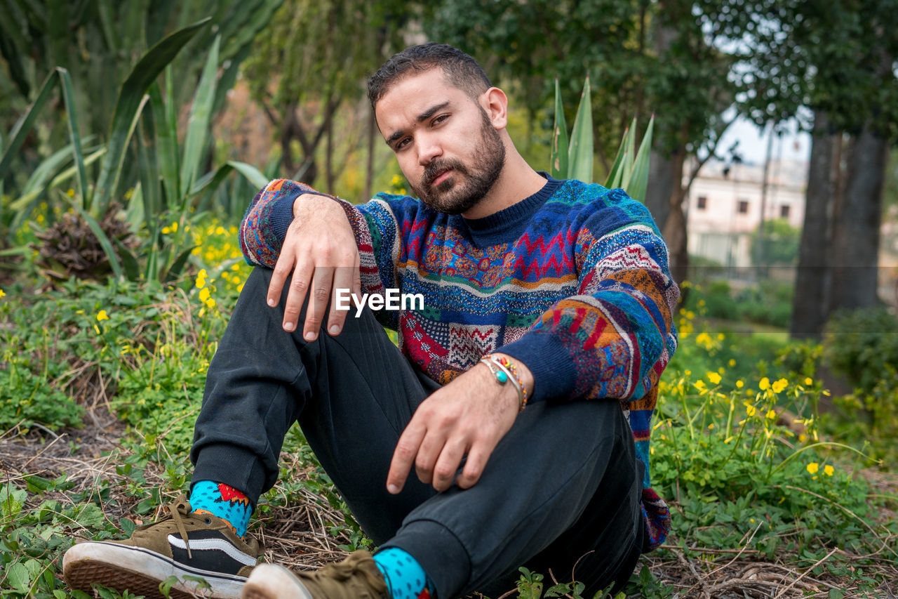 Caucasian model sitting on the ground in a public park