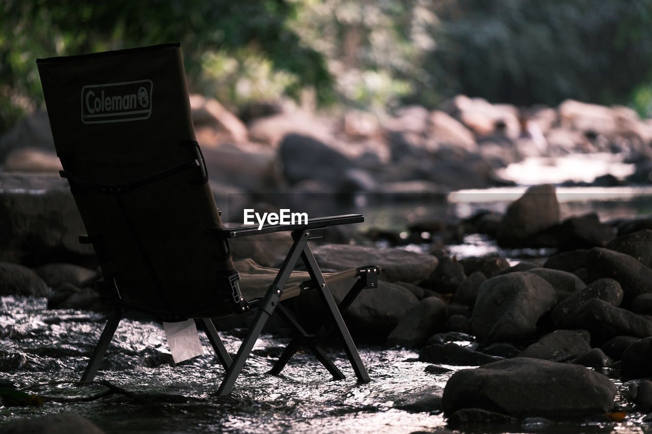 CLOSE-UP OF ABANDONED CHAIRS ON ROCKS