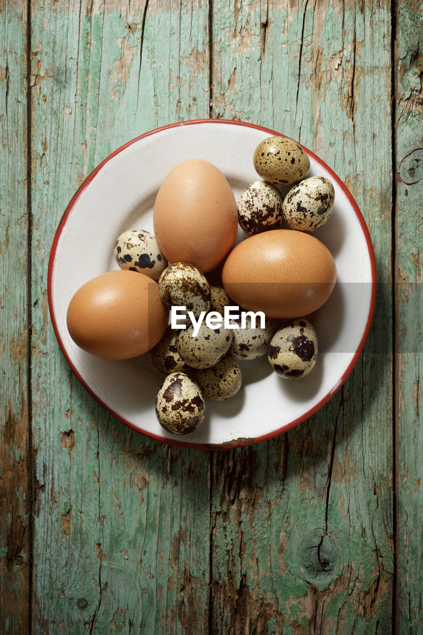 Quail and chicken eggs on a wooden table.