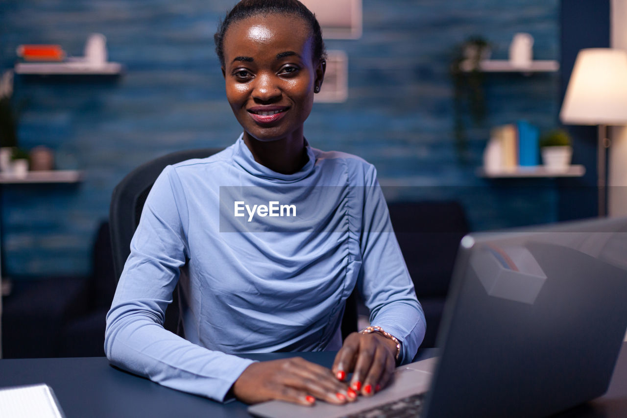 portrait of young woman using laptop at office