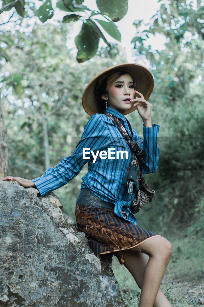 Young woman with traditional costume from java is looking away while standing against tree