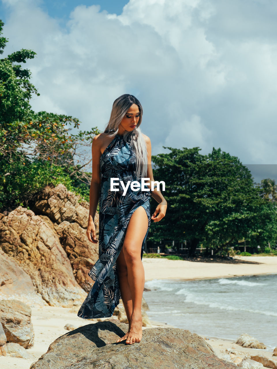 Young trans woman standing on rock against sky