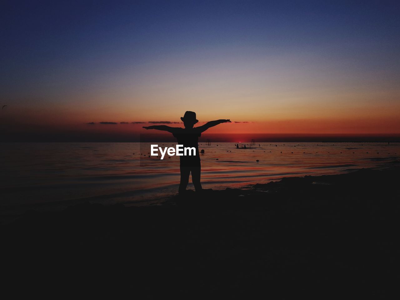 SILHOUETTE MAN STANDING AT BEACH DURING SUNSET