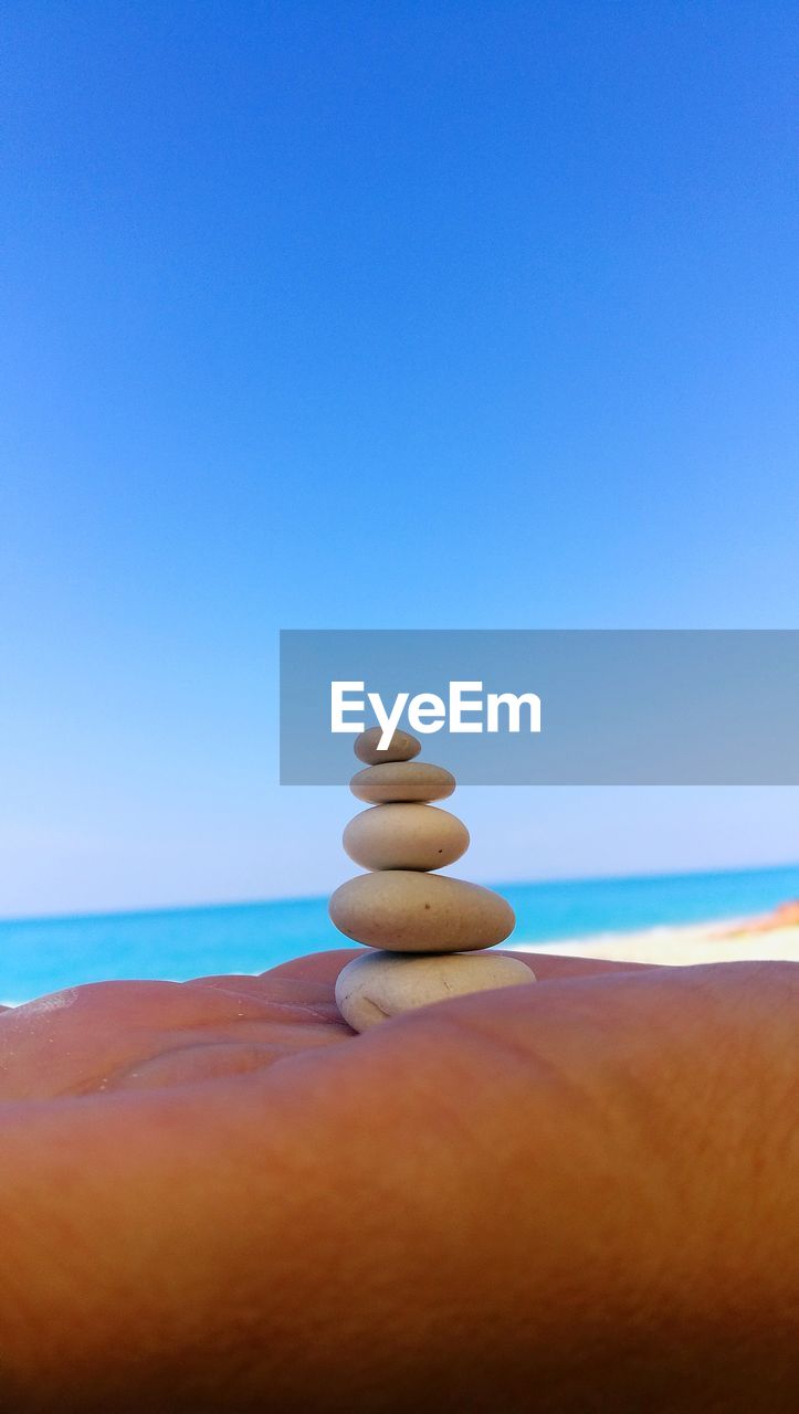 Stack of stones on beach against clear blue sky