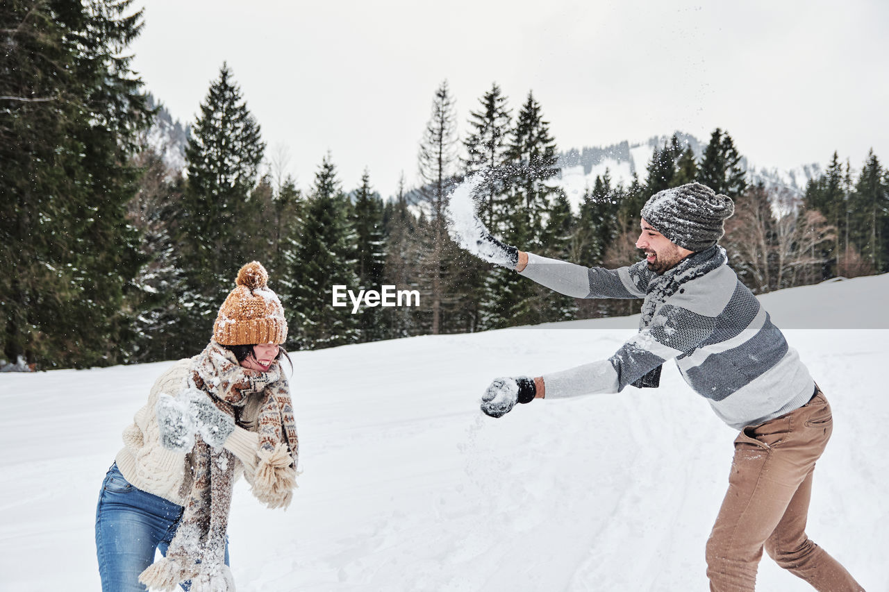 Young couple in winter sweaters having a snowball fight outdoors. snow, happy, fun.