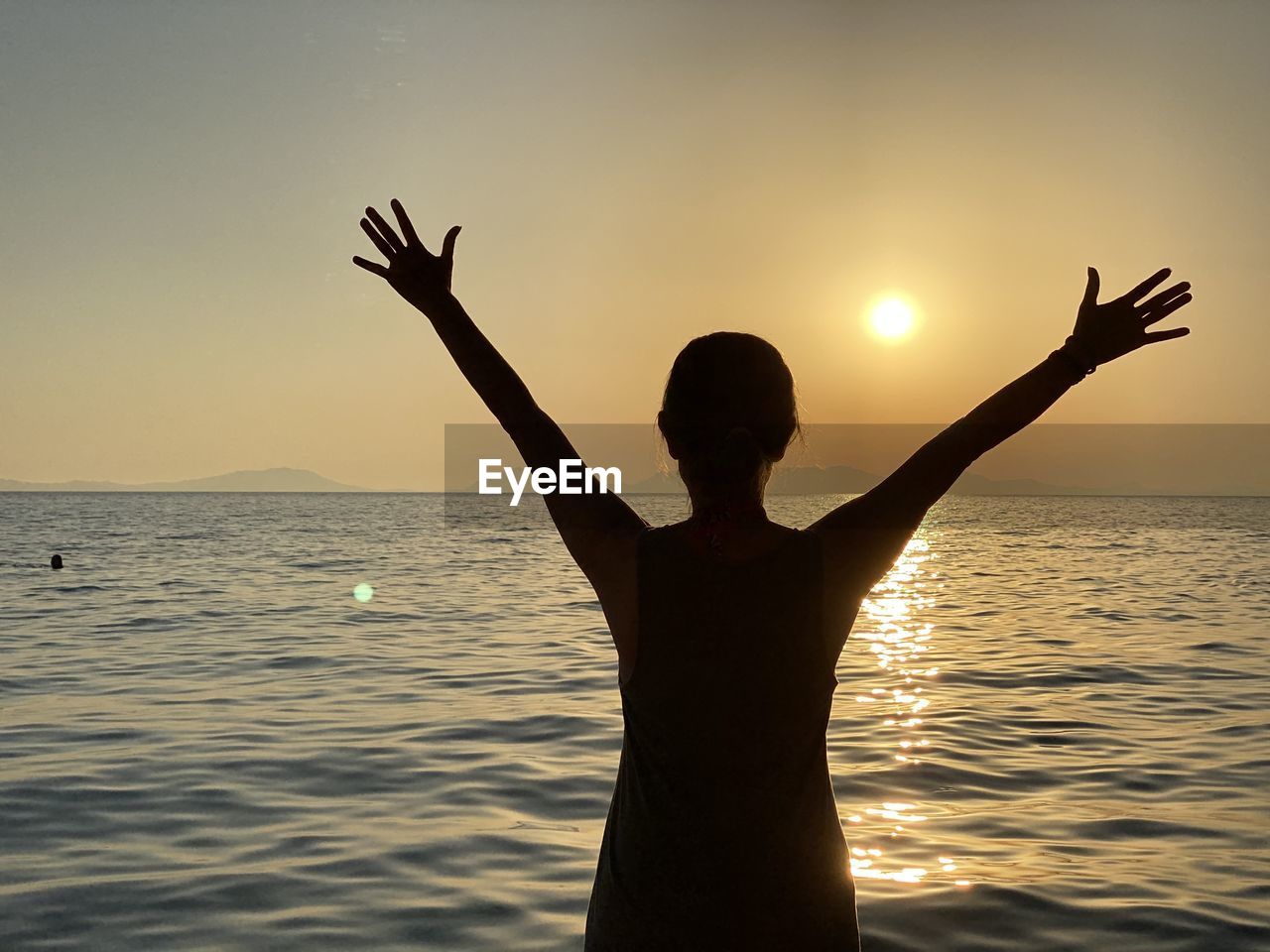 REAR VIEW OF SILHOUETTE PERSON STANDING AT SEA SHORE AGAINST SKY