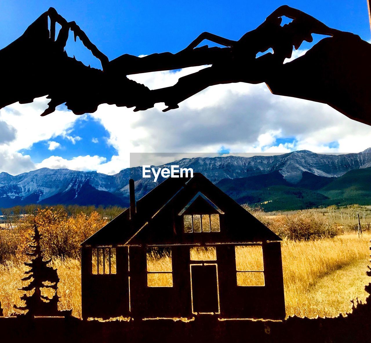 SILHOUETTE HOUSE AGAINST MOUNTAIN RANGE