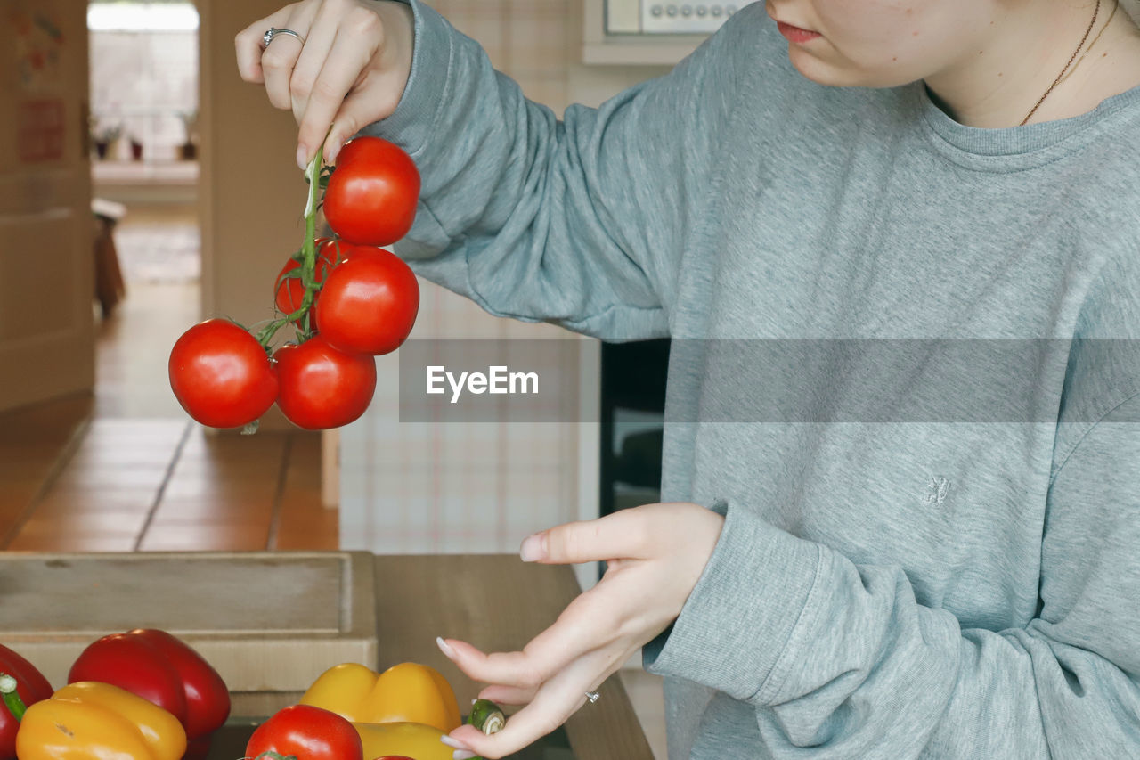 Midsection of woman holding red tomatoes at home