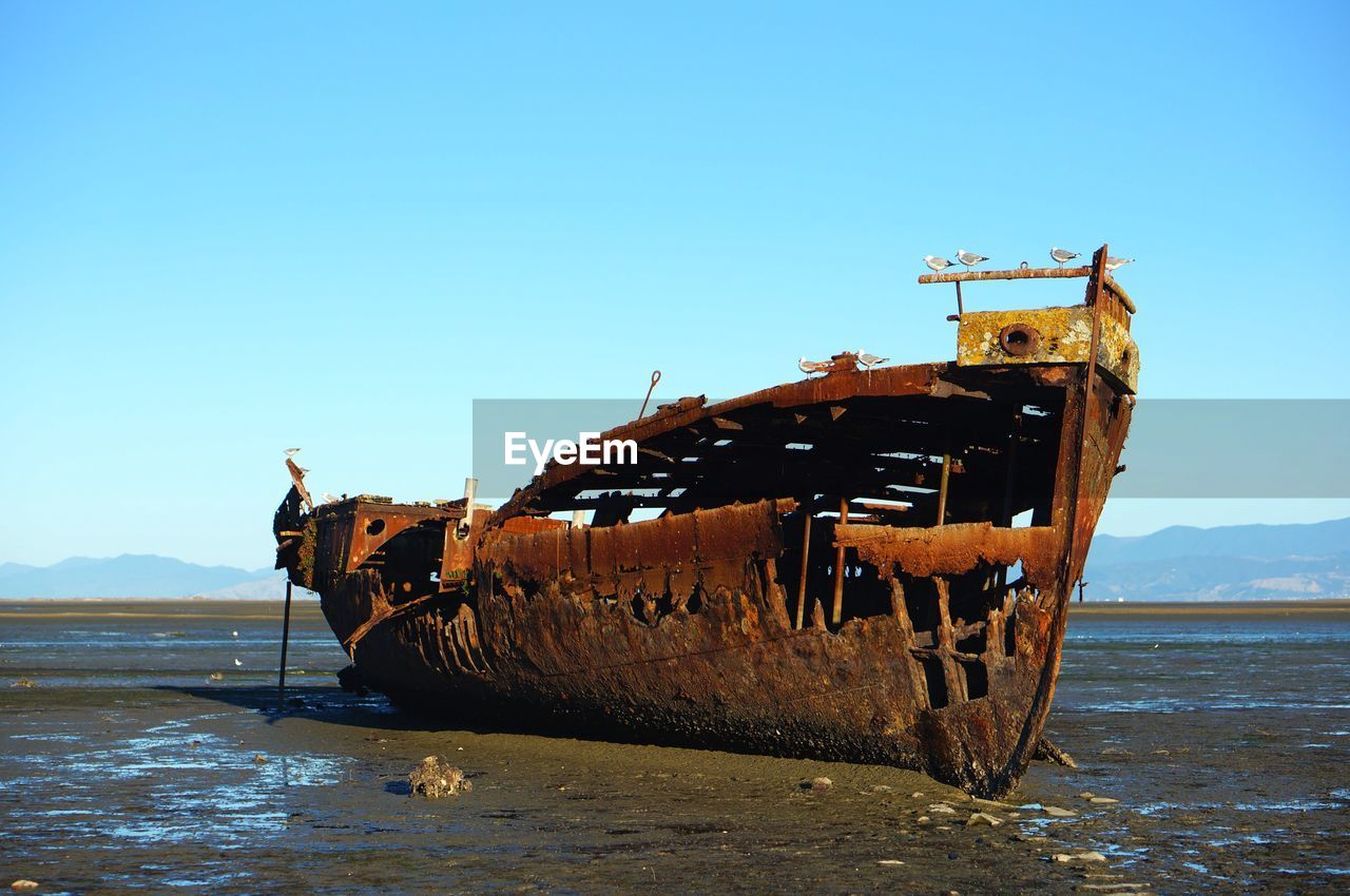 Abandoned boat on beach against clear sky