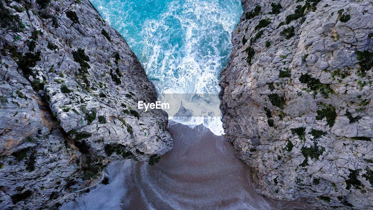 HIGH ANGLE VIEW OF ROCK FORMATIONS BY SEA