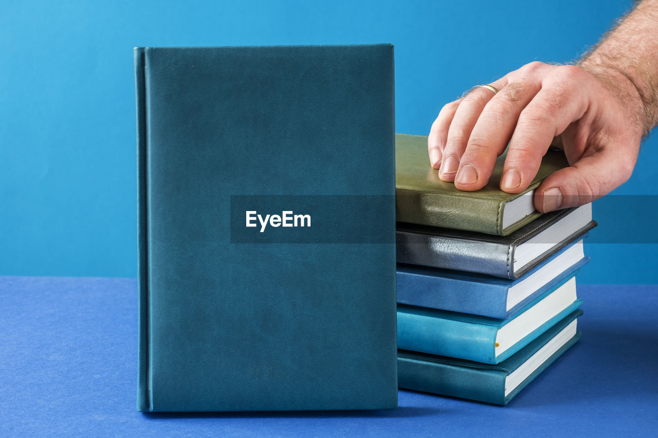 CLOSE-UP OF HUMAN HAND ON BLUE TABLE