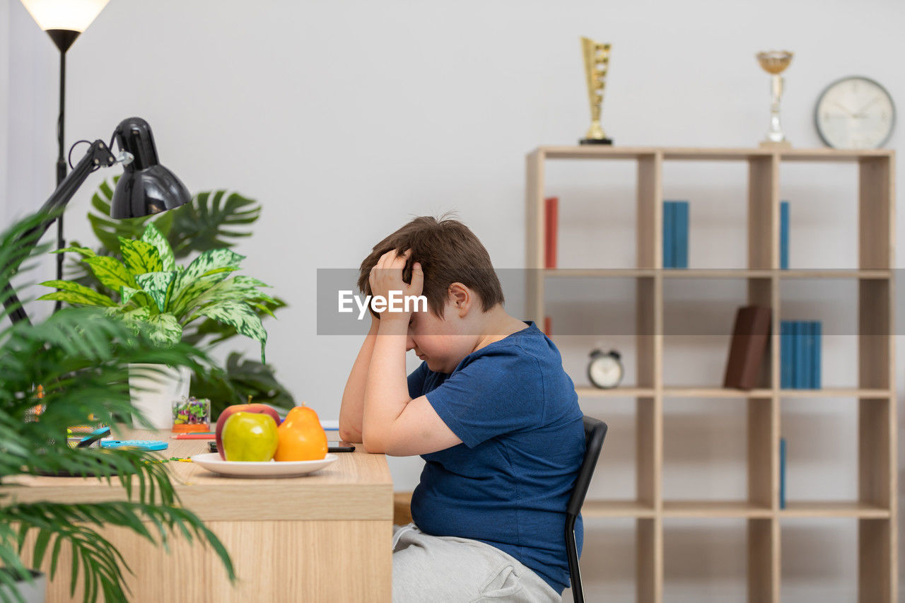 side view of boy playing with toy blocks on table at home