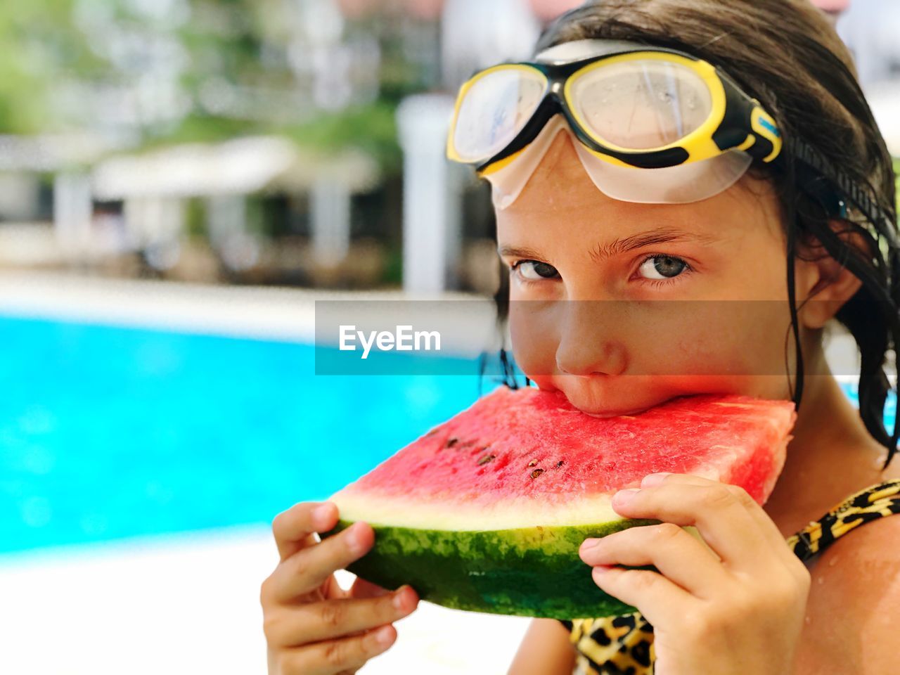 Portrait of girl eating watermelon at swimming pool