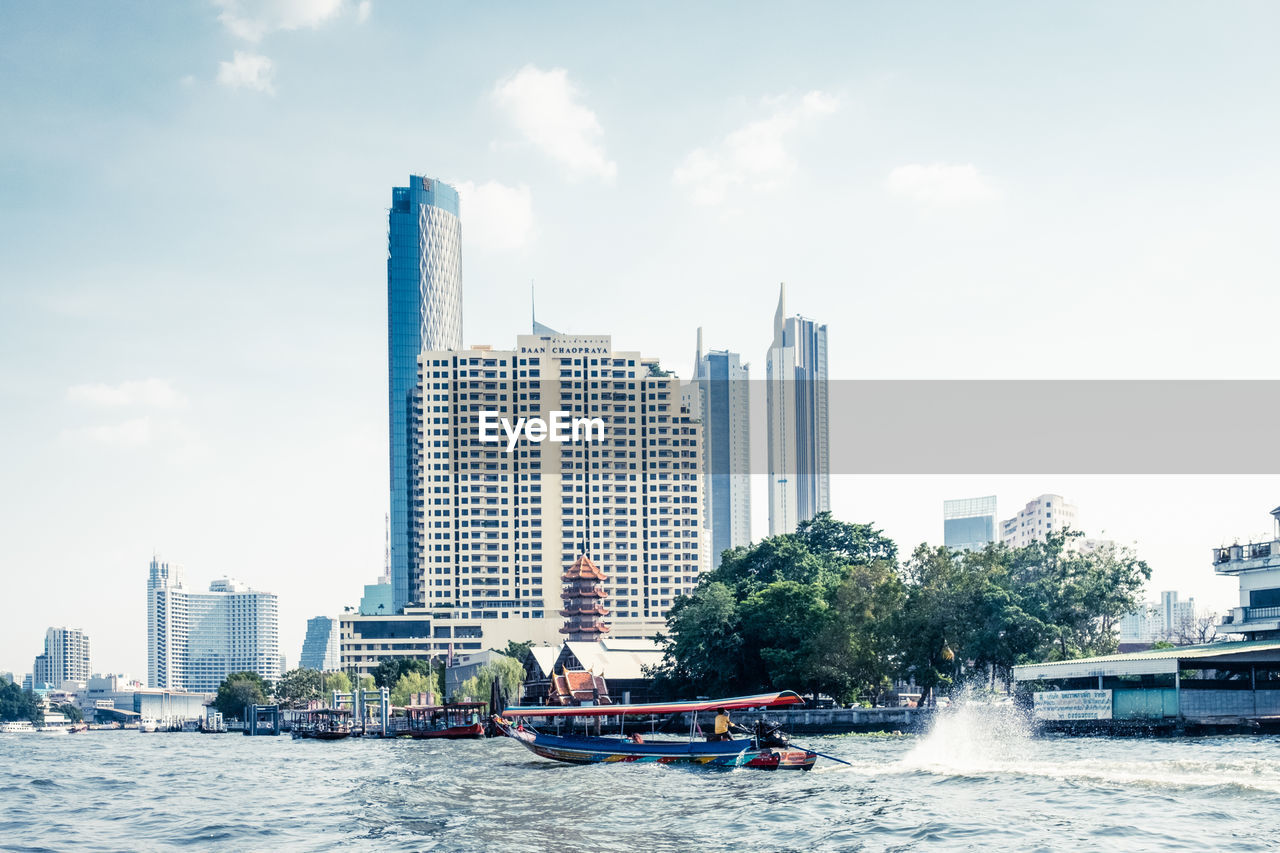 BUILDINGS BY RIVER AGAINST SKY