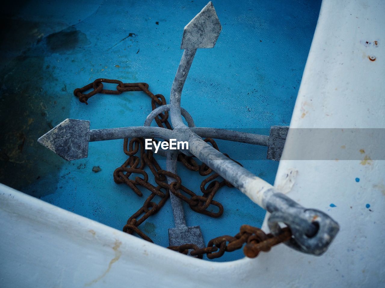 CLOSE-UP OF RUSTY CHAIN AGAINST WALL