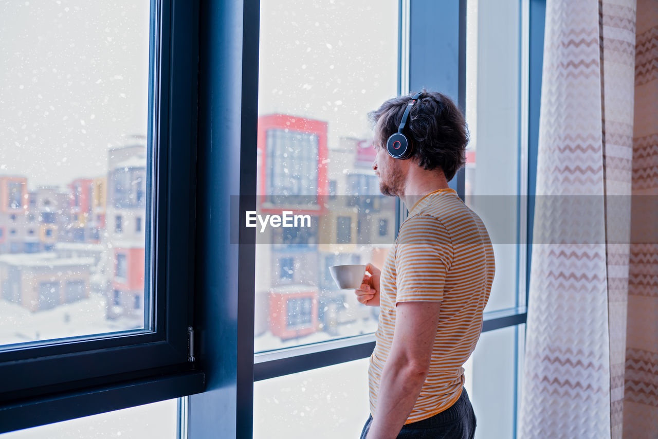 Adult programmer with a cup of tea talks to coworkers using a wireless headset 