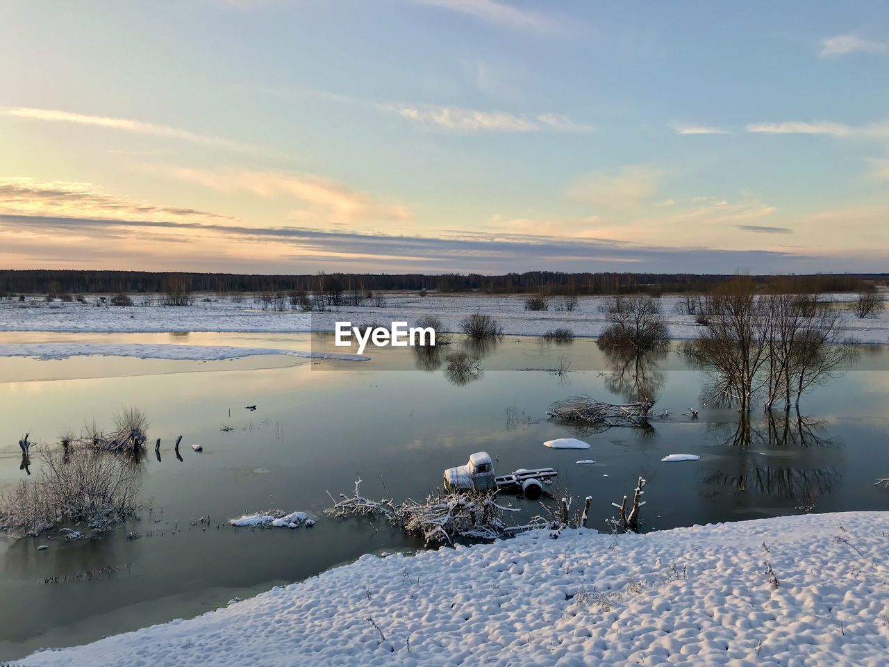 Scenic view of frozen lake against sky during sunset