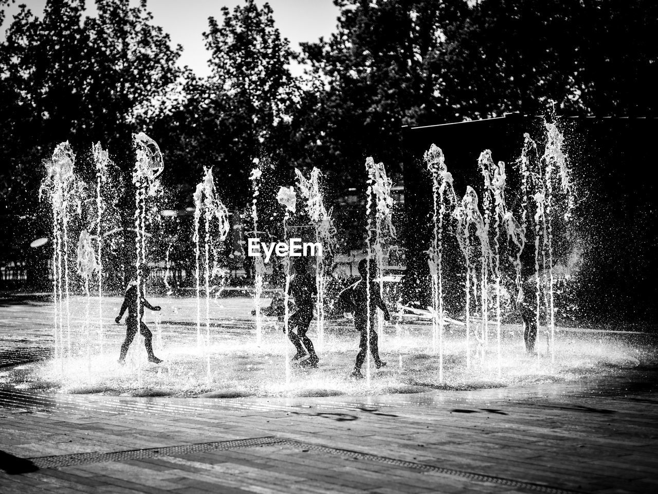 Children playing in fountain on sunny day