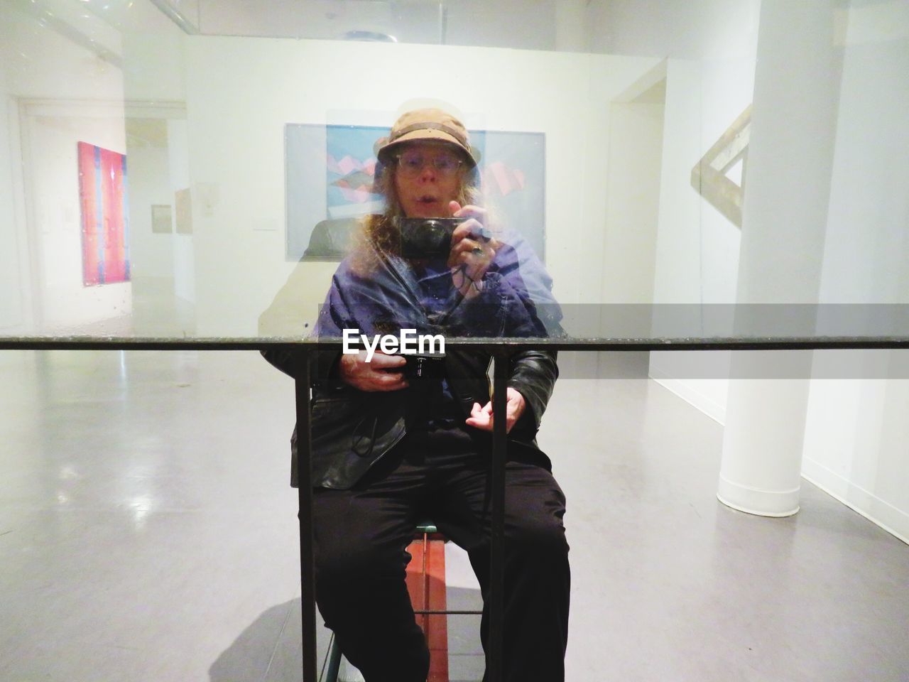 Woman photographing man with camera reflecting on glass