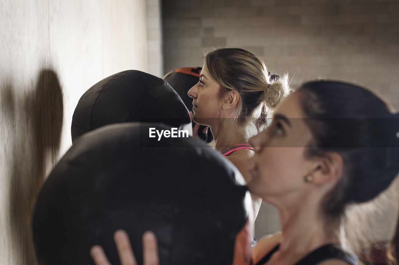 Side view of determined sportswomen exercising with medicine balls in gym