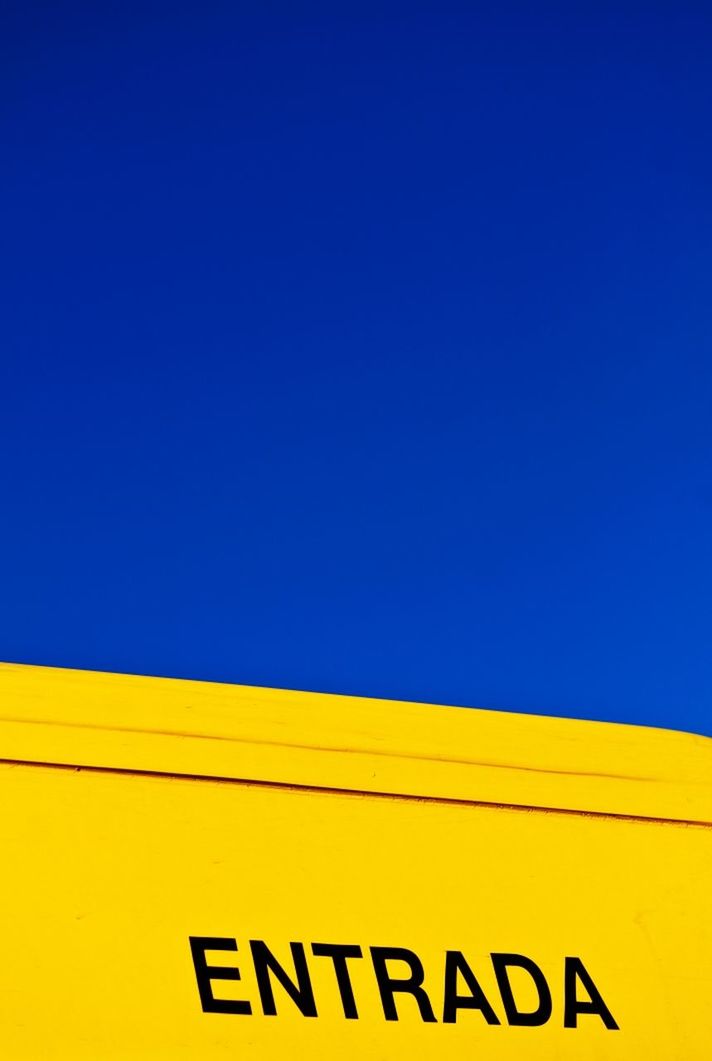 Close-up of text on yellow surface against blue sky