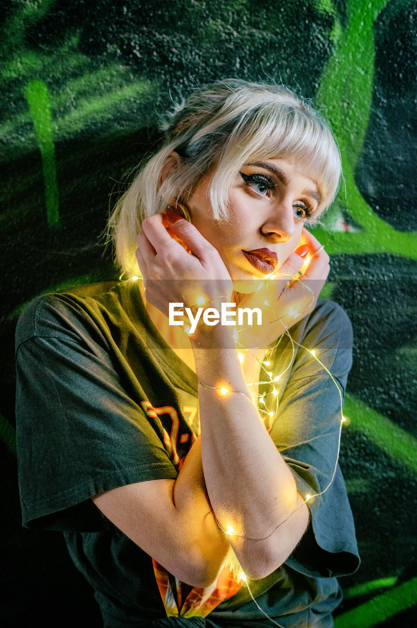 Young woman with illuminated lighting equipment looking away 