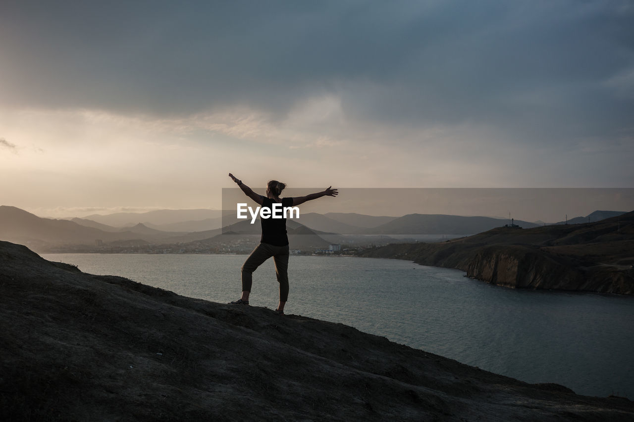 FULL LENGTH OF MAN STANDING ON SHORE AGAINST SKY