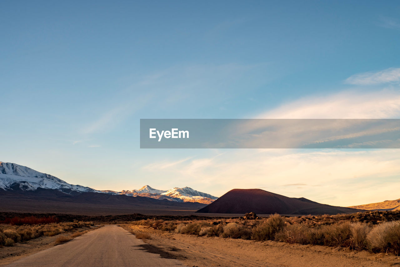 Road leading towards mountains against sky