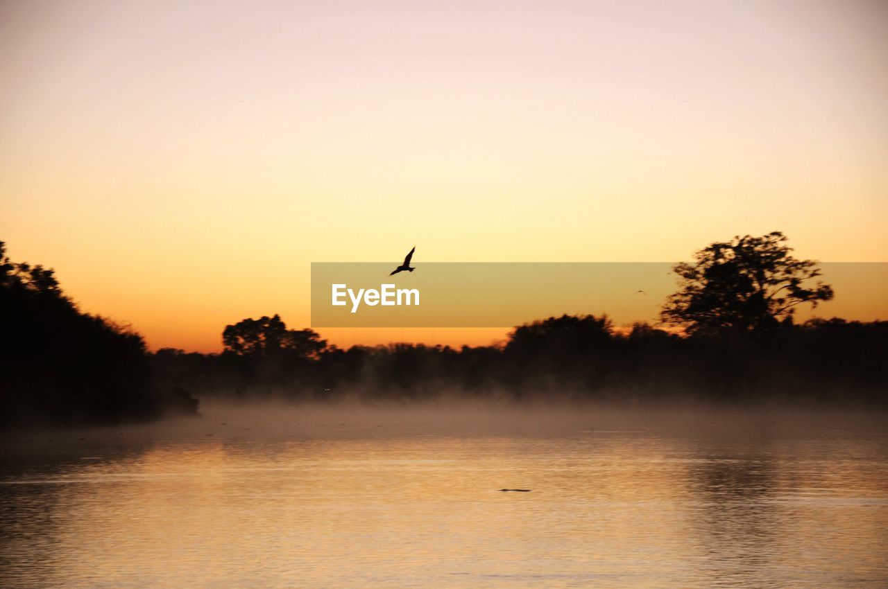 SCENIC VIEW OF LAKE AGAINST SKY AT SUNSET