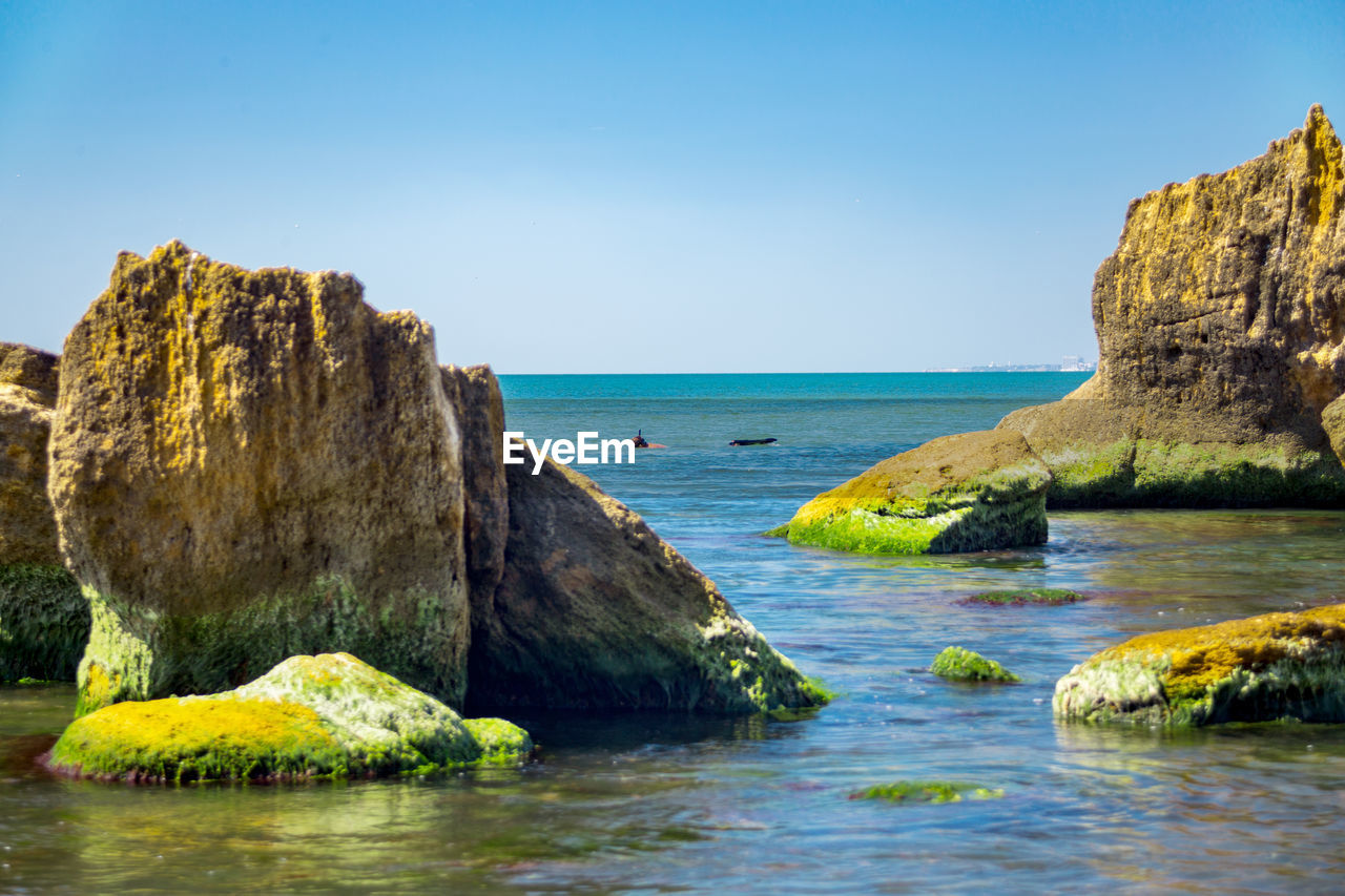 Scenic view of rocks in sea against clear sky