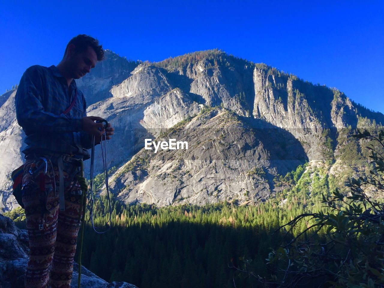 Man holding harness while standing against mountain at yosemite national park