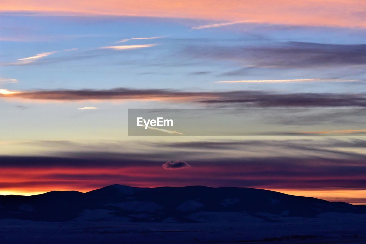 SCENIC VIEW OF SILHOUETTE MOUNTAINS AGAINST DRAMATIC SKY