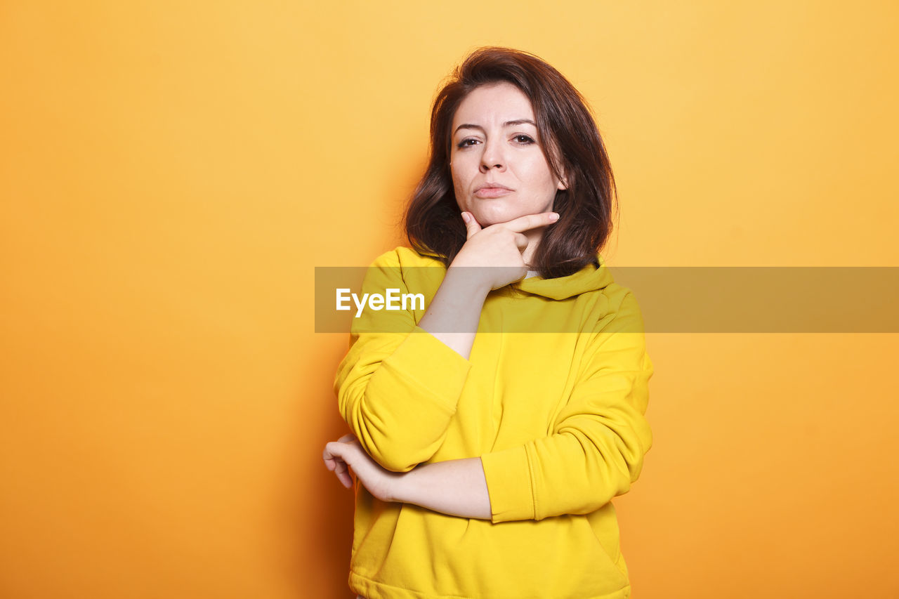 portrait of beautiful young woman standing against yellow background