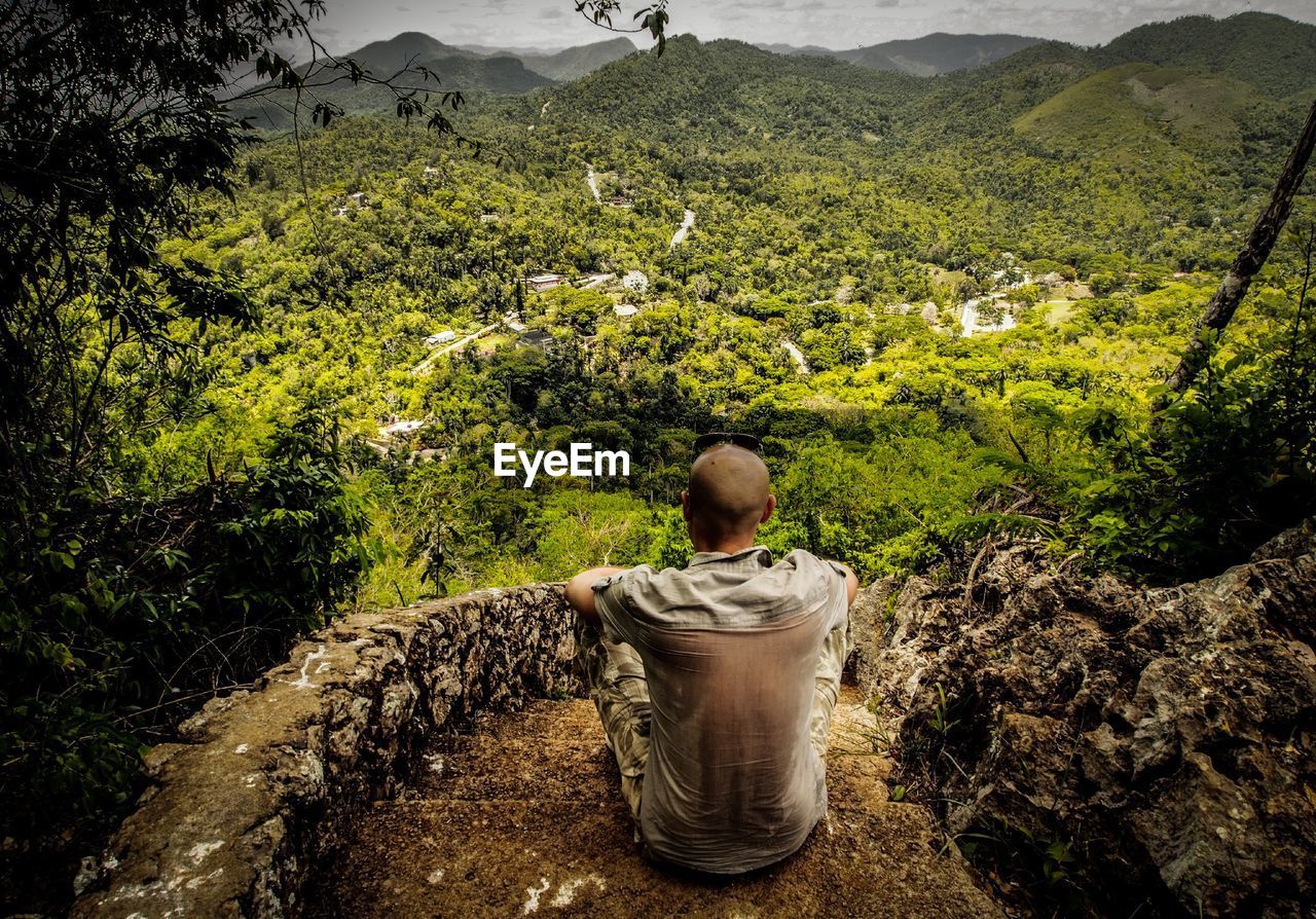 Rear view of man looking at mountains while sitting on steps