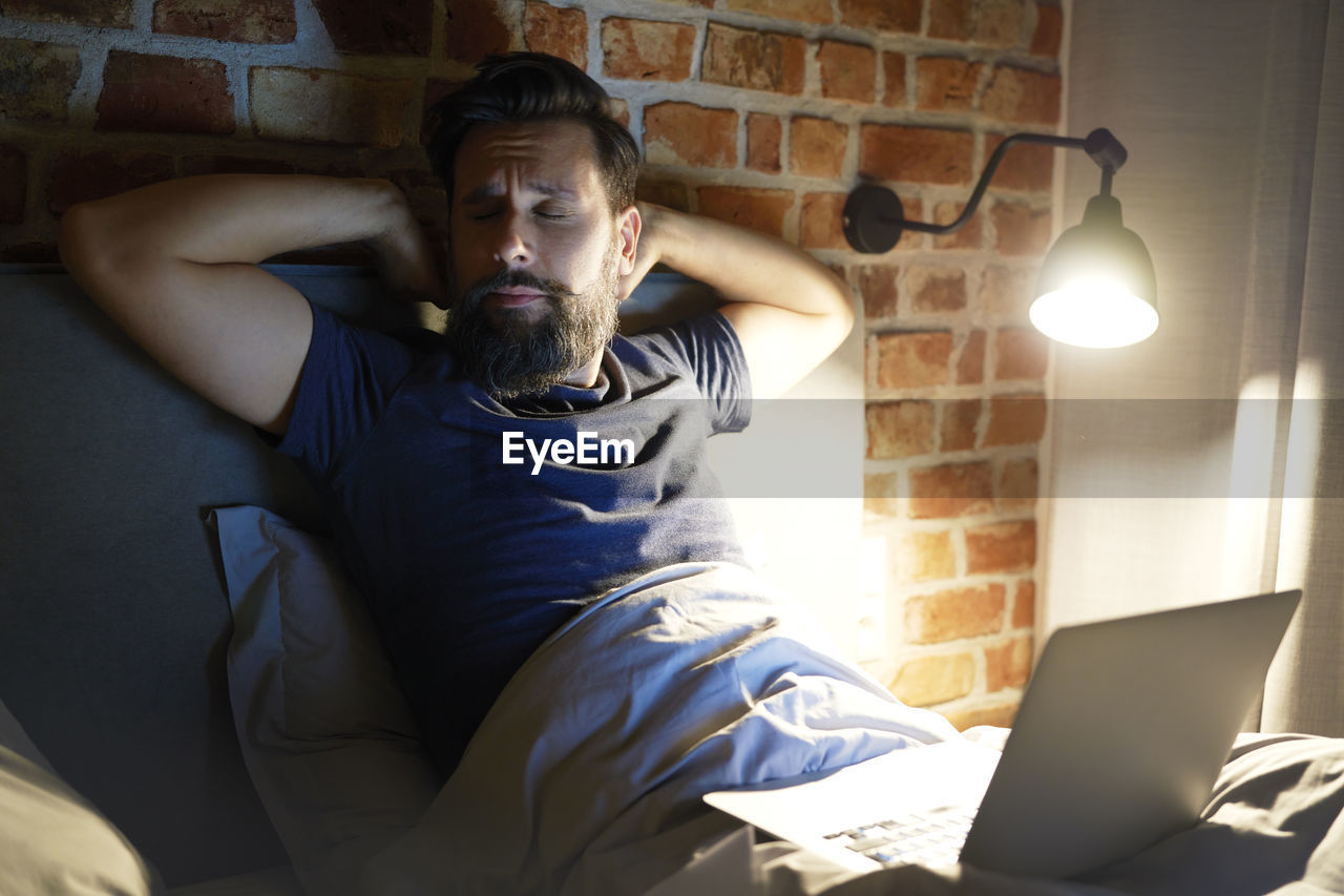 Businessman sleeping with laptop in bedroom