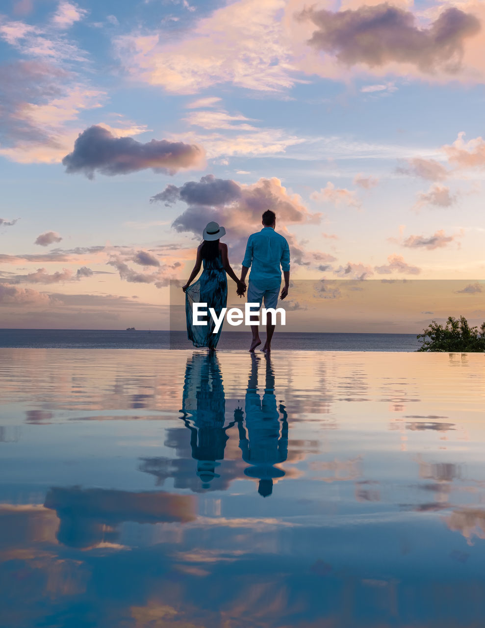 rear view of woman standing on beach against sky during sunset