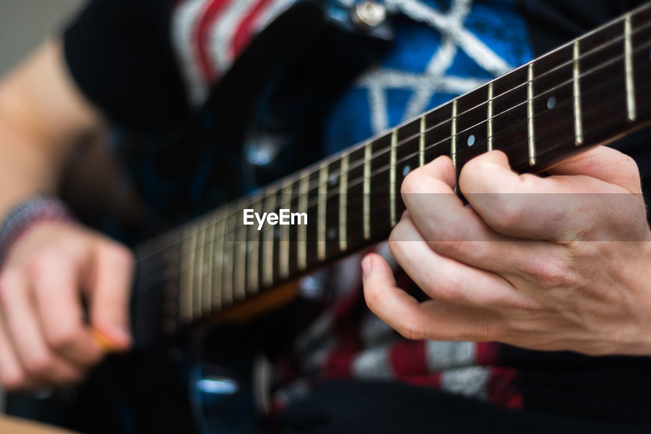 Midsection of man playing guitar