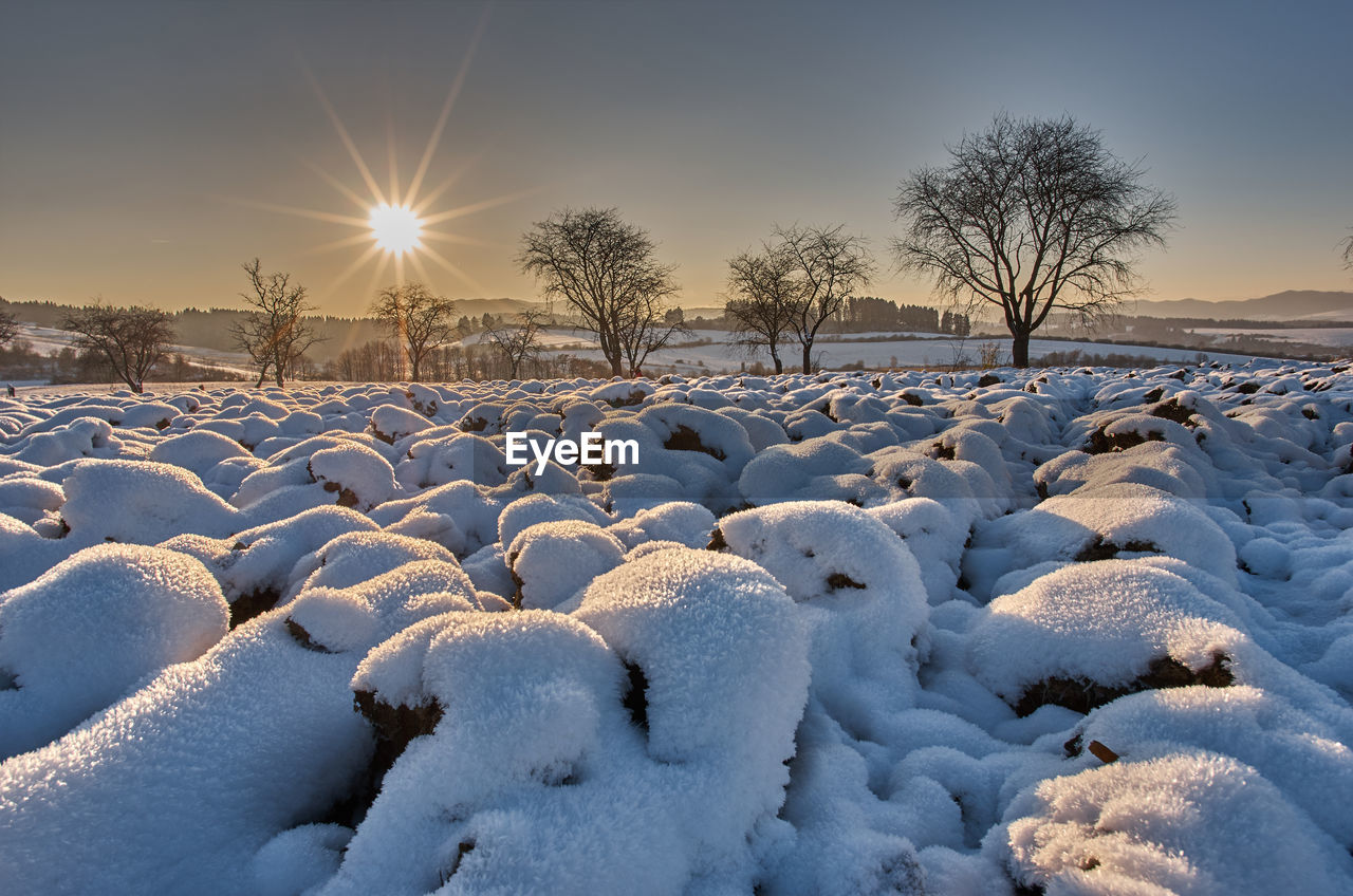 SNOW COVERED FIELD AGAINST SKY AT SUNSET