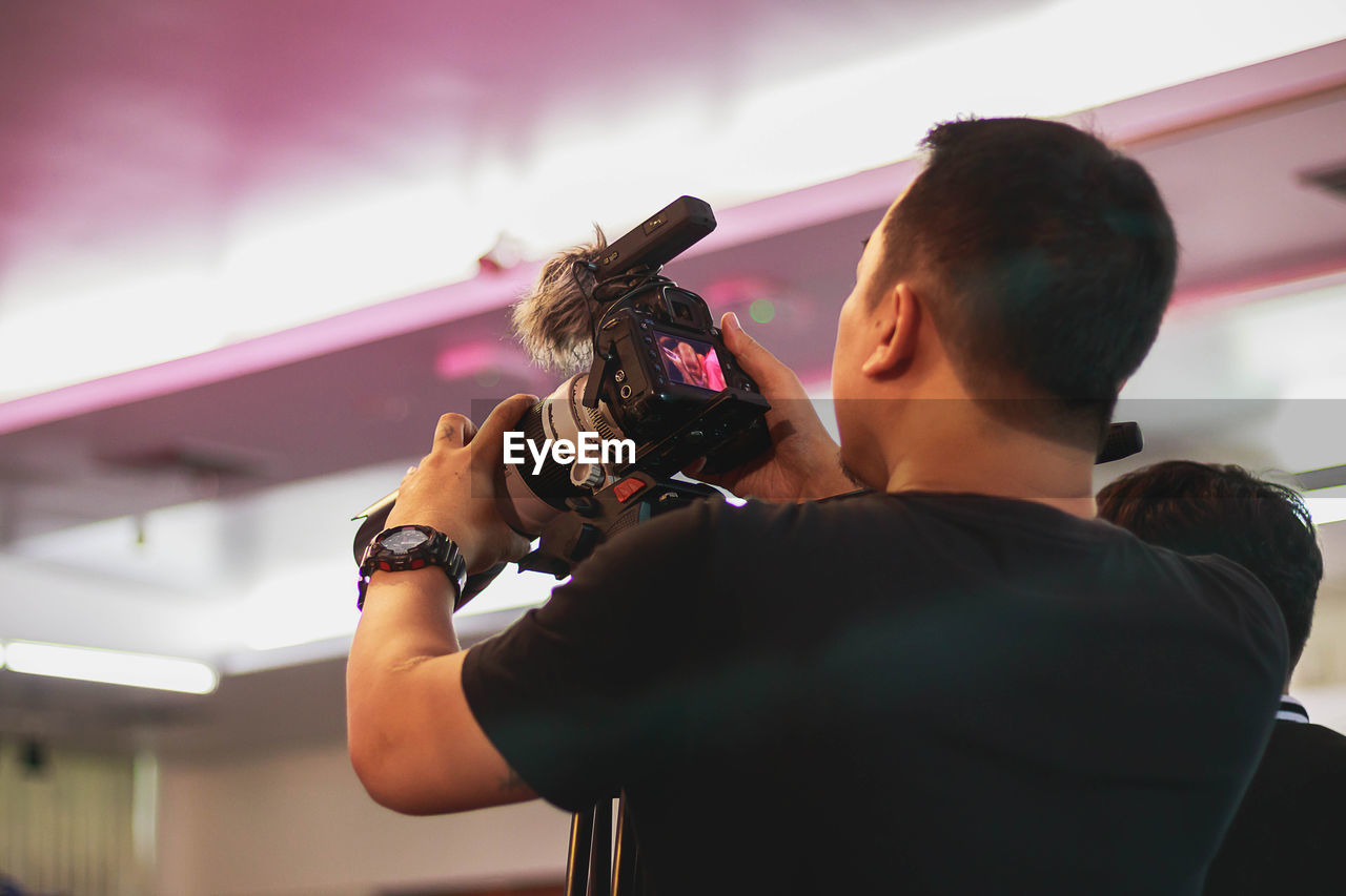 Man photographing through camera against ceiling