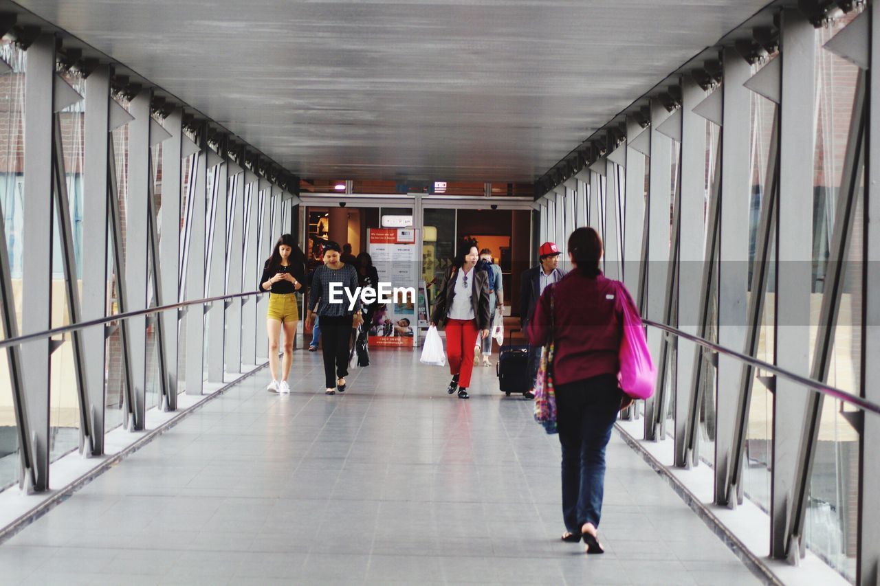 REAR VIEW OF WOMAN STANDING IN CORRIDOR