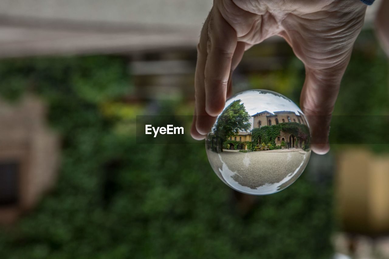 Cropped hand of person holding crystal ball in city