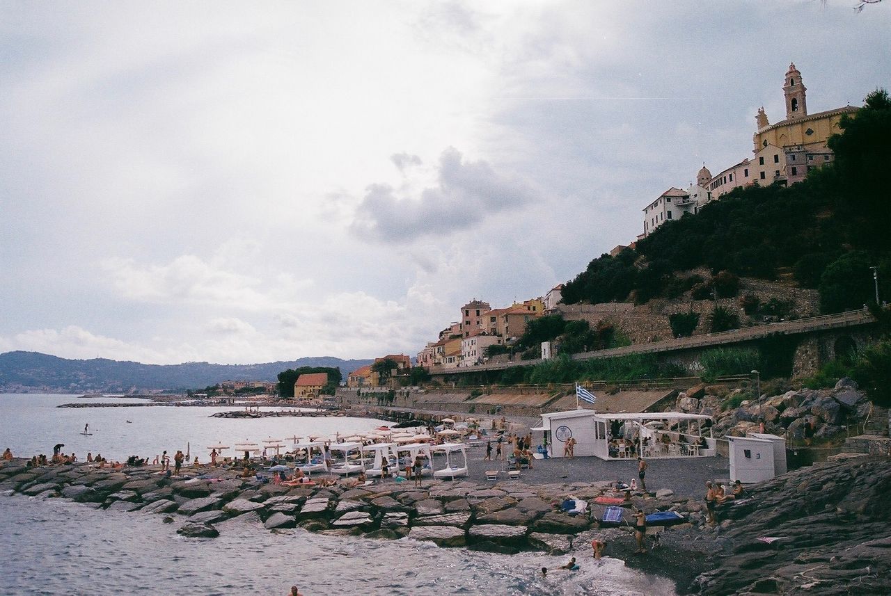 Scenic view of beach by buildings in town against sky