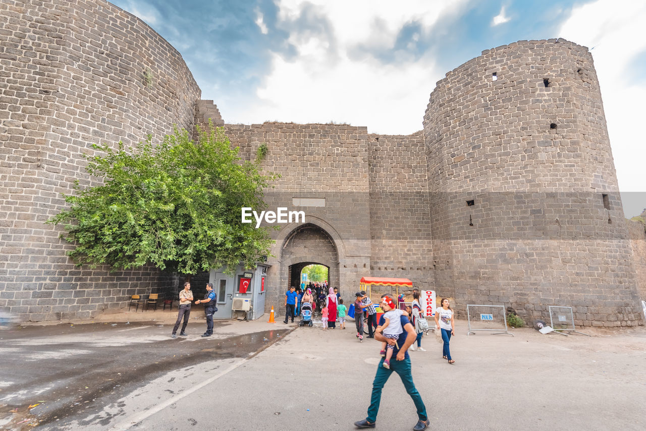 PEOPLE IN FRONT OF HISTORICAL BUILDING AGAINST SKY