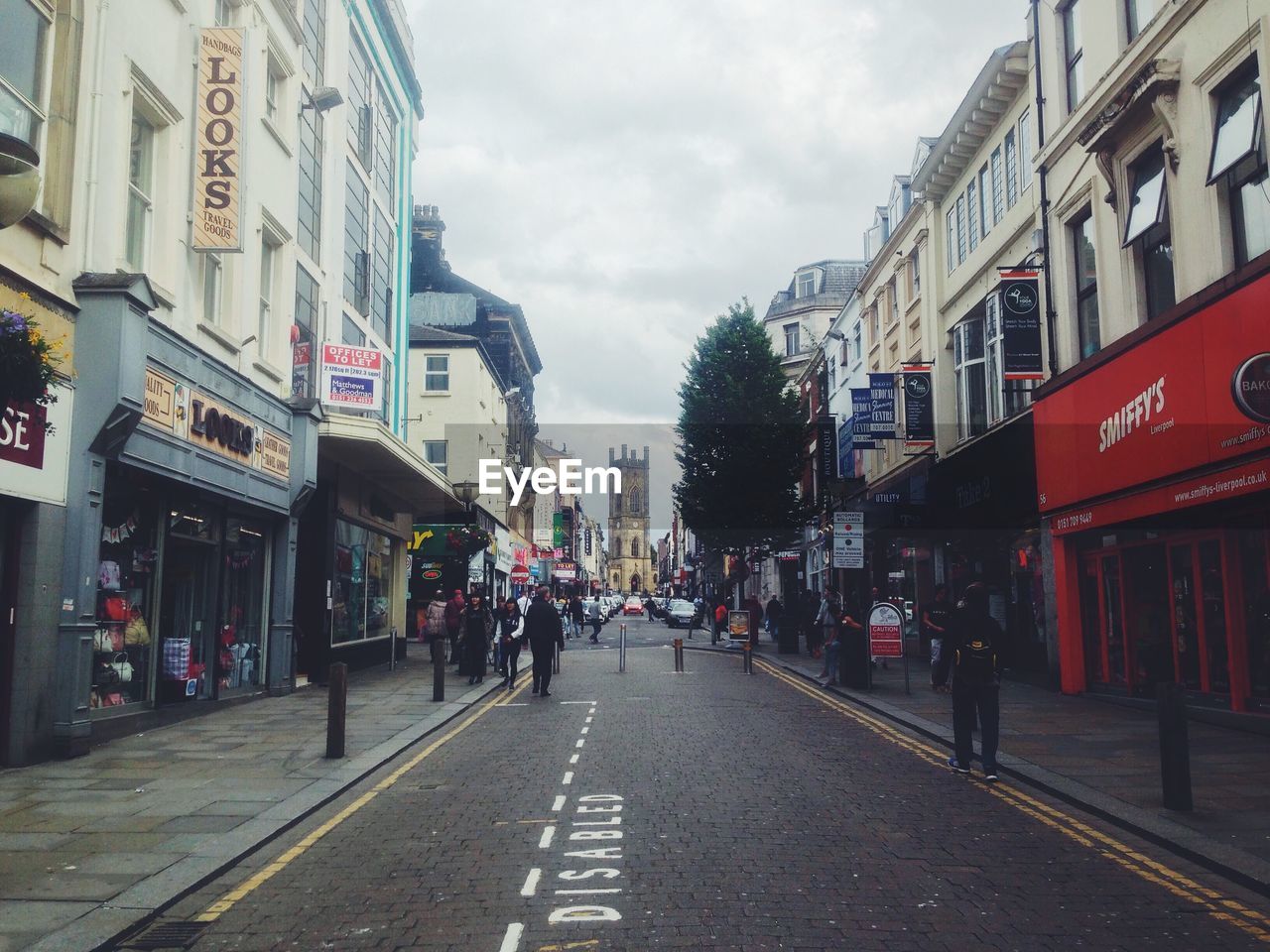 STREET AMIDST BUILDINGS IN CITY AGAINST SKY