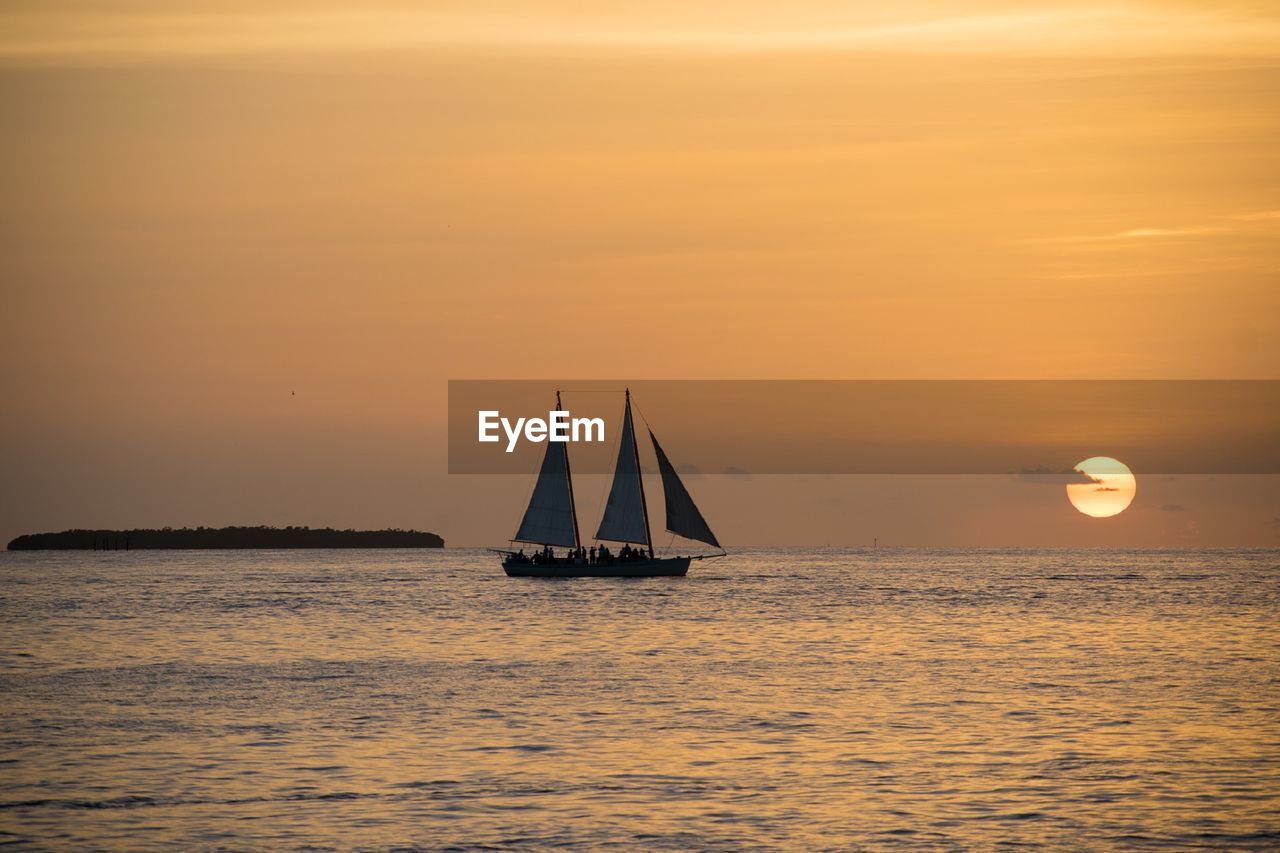 Sailboat sailing on sea against sky during sunset