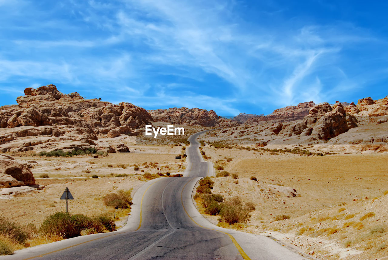 Road leading towards mountains against sky