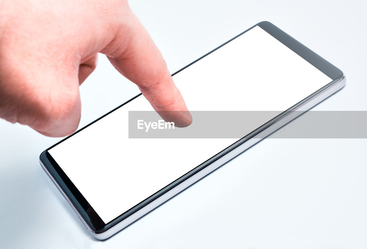 Close-up of hand touching blank phone screen over white background