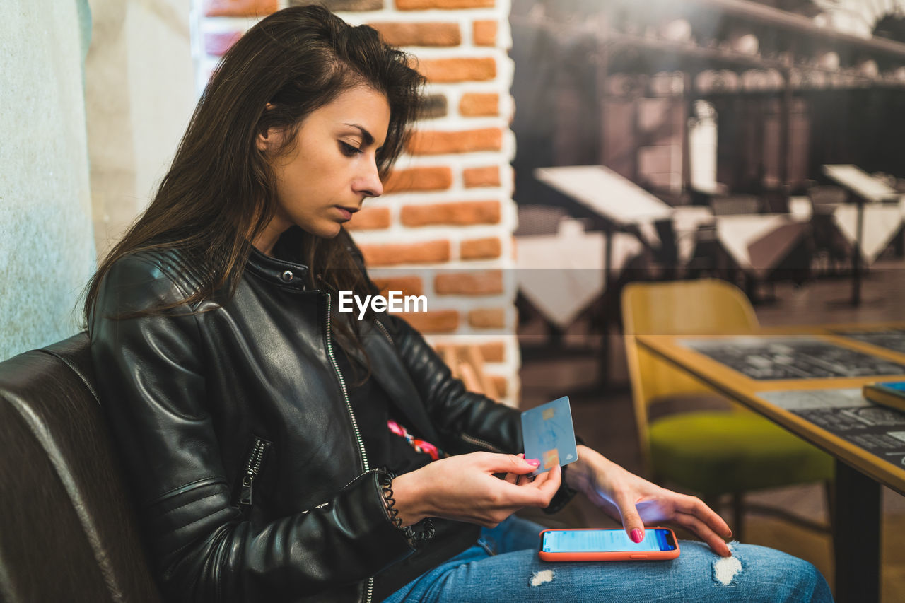 Young woman using phone on table