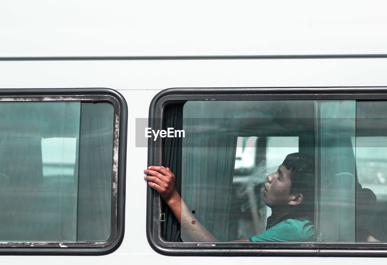 PORTRAIT OF MAN LOOKING THROUGH WINDOW