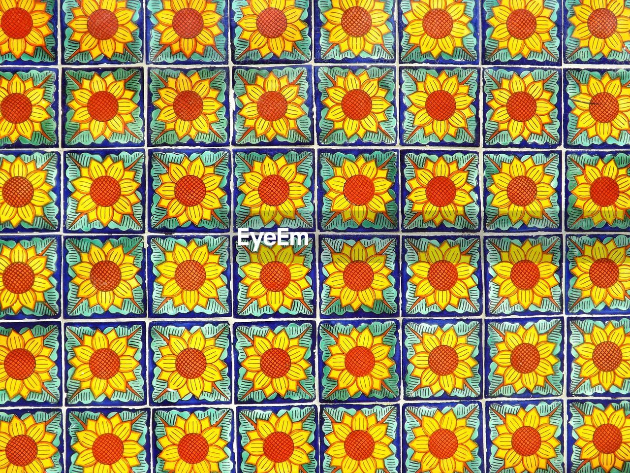 FULL FRAME SHOT OF YELLOW FLOWERING PLANTS ON FLOOR AGAINST ORANGE WALL